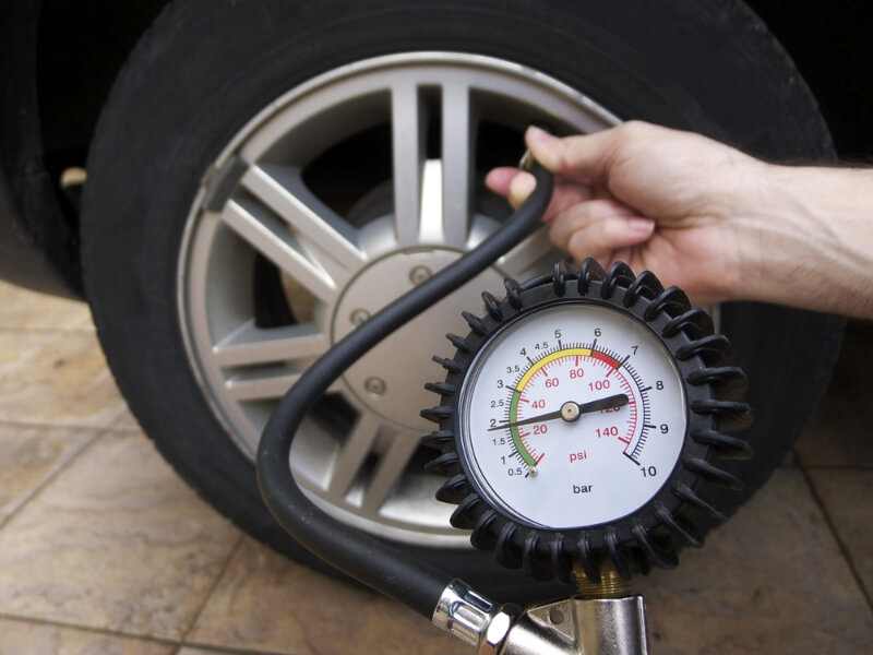 Man ajusting the pressure in his tire to achieve better fuel economy