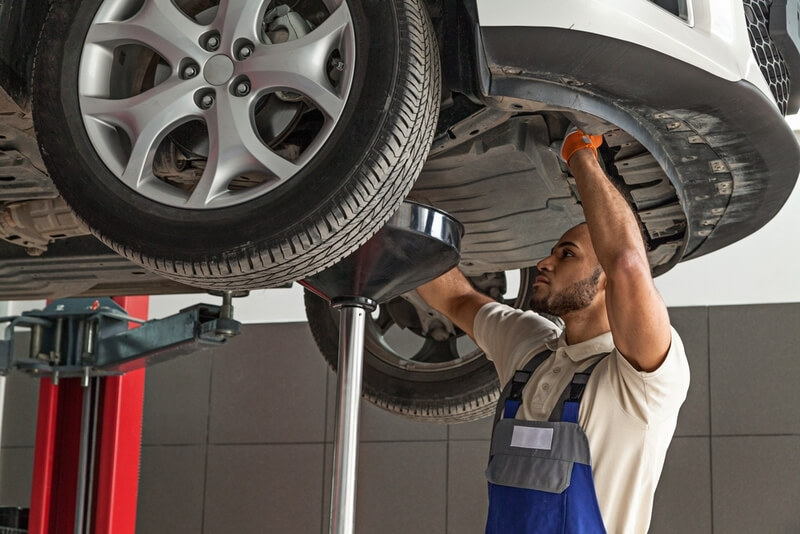Auto mechanic draining engine oil