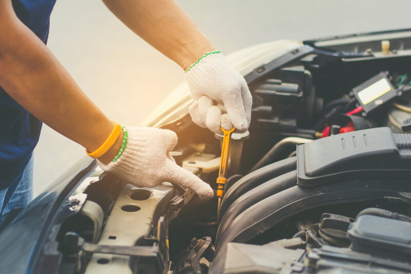Auto mechanic checking the engine oil level