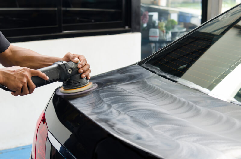 Technician using an orbital polisher to apply polishing compound