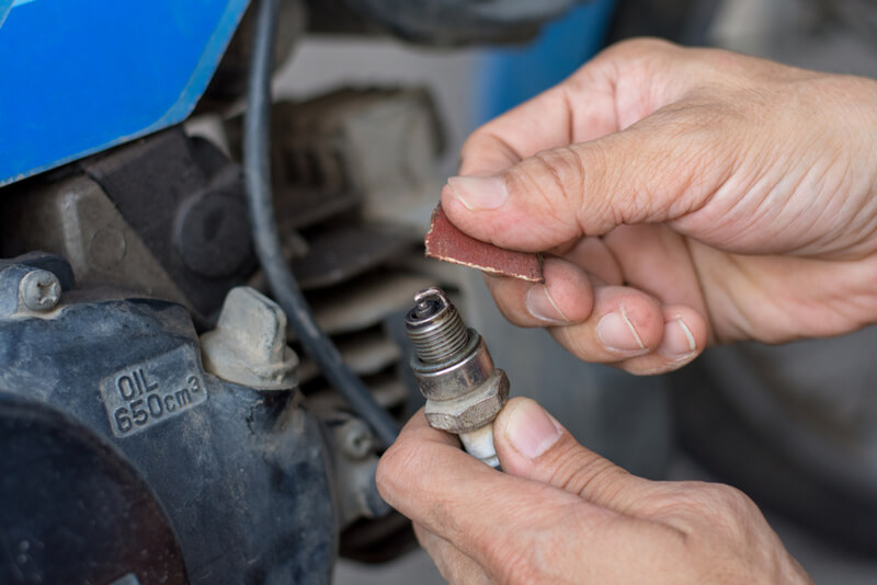 Auto mechanic cleaning a spark plug