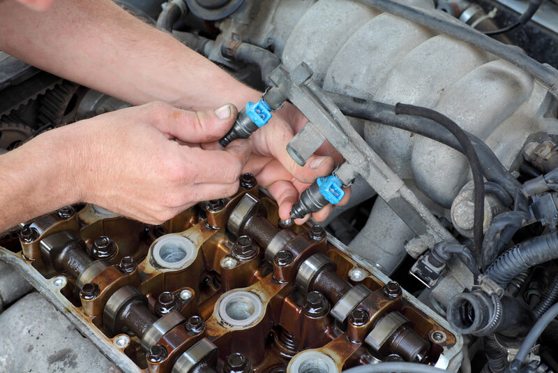 Auto mechanic performing injector maintenance