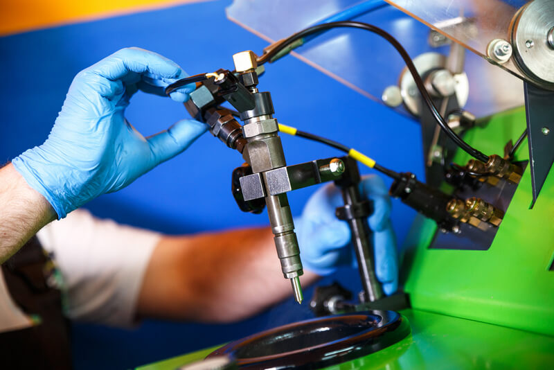 Technician testing fuel injectors spray pattern