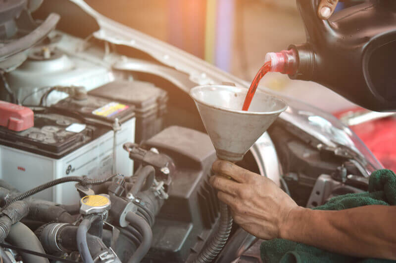 Auto mechanic replacing automatic transmission fluid