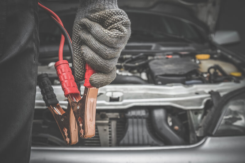 Man hotwiring a car using jumper cables