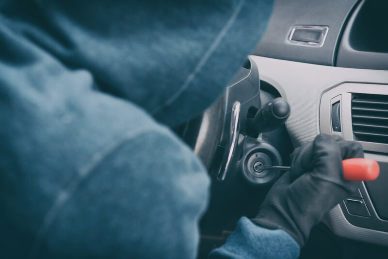 Man hotwiring a car with a screwdriver